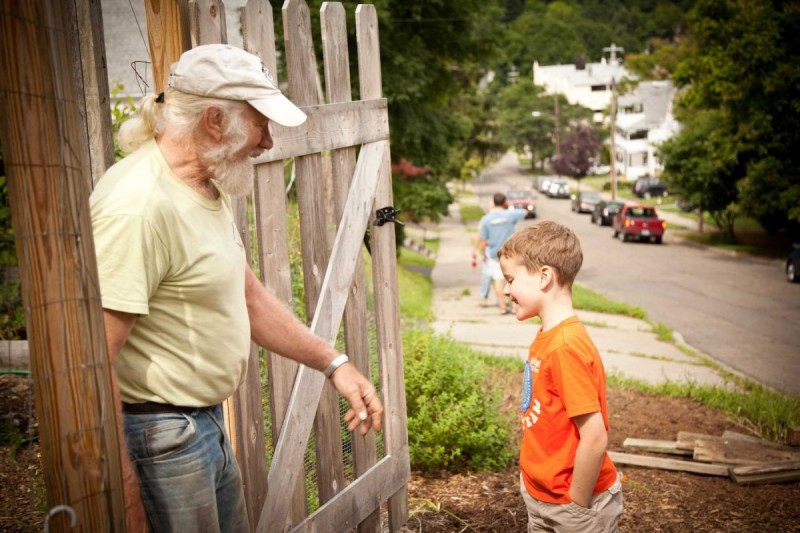 Professor Dick Andrus greets a neighborhood youth at a VINES community garden in Binghamton.