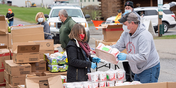 Volunteers for the Food Bank of the Southern Tier prepare food to be loaded into car trunks for those experiencing food insecurity.
