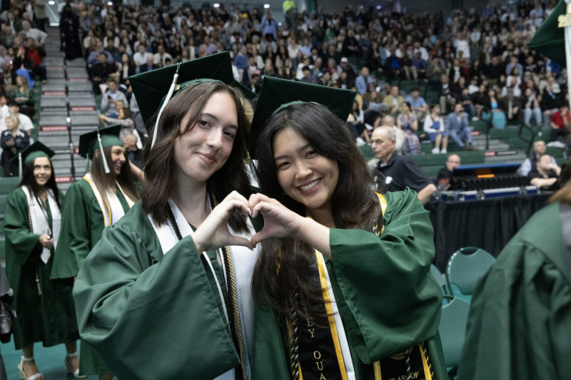 Graduates at Harpur College's 2026 morning Commencement ceremony form a heart with their hands.