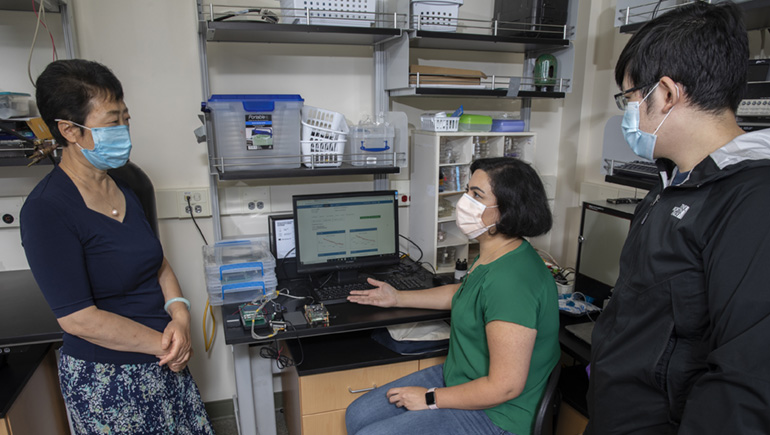 Shuxia Susan Lu, professor of Systems Science and Industrial Engineering at the Thomas J. Watson College of Engineering and Applied Science, meets with graduate students Dong Dinh, and, Behnaz Malaei.