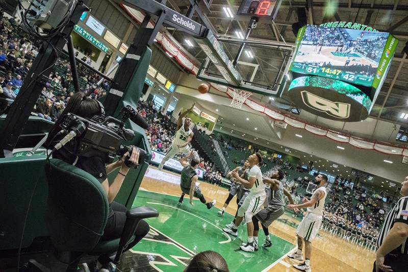 A member of the Binghamton University basketball broadcast team works a camera under the hoop during an early season game for the Bearcats.