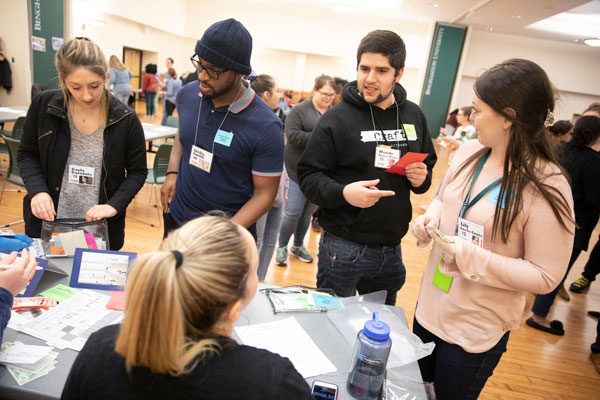 Luis Midence (black sweatshirt), a student in the Master of Public Health Program, purchases food and clothing for his family during a simulation event that is part of Binghamton's interprofessional education program.
