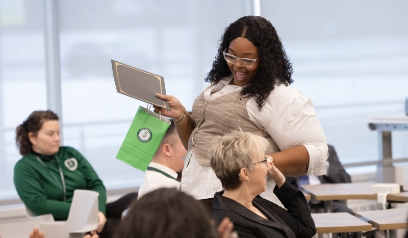 Pharmacy Technician Program graduates Sharavia (Rae) Weathers and Teresa Swankoski give each other a high five after receiving their certificates of completion.