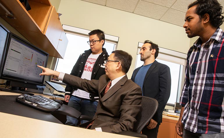 Ning Zhou, an associate professor of electrical and computer engineering, explains a concept about power grids to, from left, graduate students Yuting Chen, Hossein Sangrody and Tawsif Ahmad.