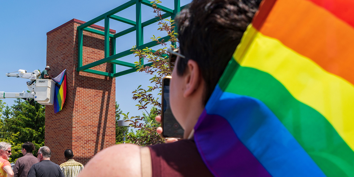 Attendees watch the installation of the Progress Pride flag.