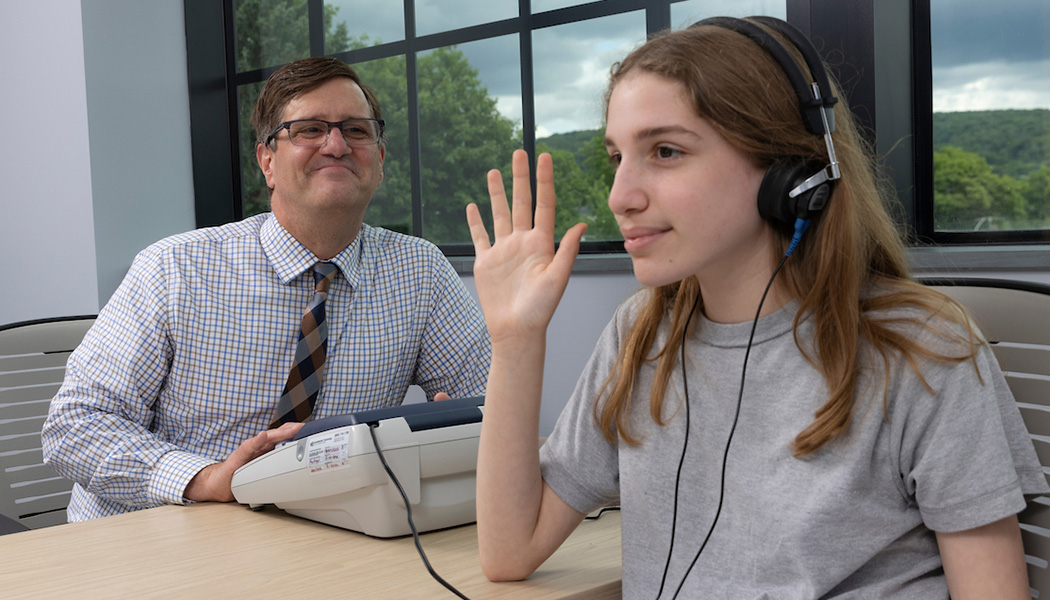 Rodney Gabel, professor and founding director of the Division of Speech and Language Pathology, conducts a hearing screening on Audrey Gabel. This test is a standard component of most speech and language evaluations.
