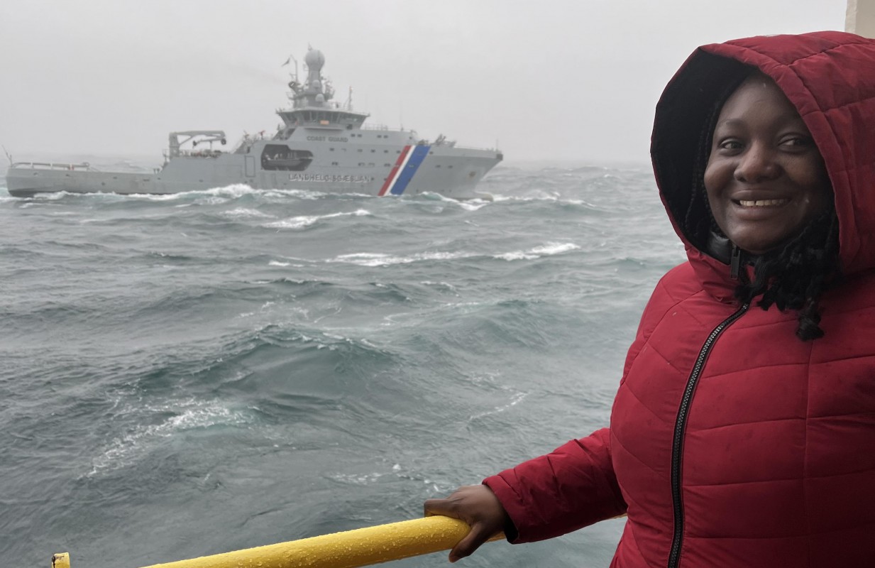 Geological sciences doctoral student Halima Ibrahim at sea aboard the JOIDES Resolution drilling vessel, with the Icelandic Coast Guard vessel Thor in view.