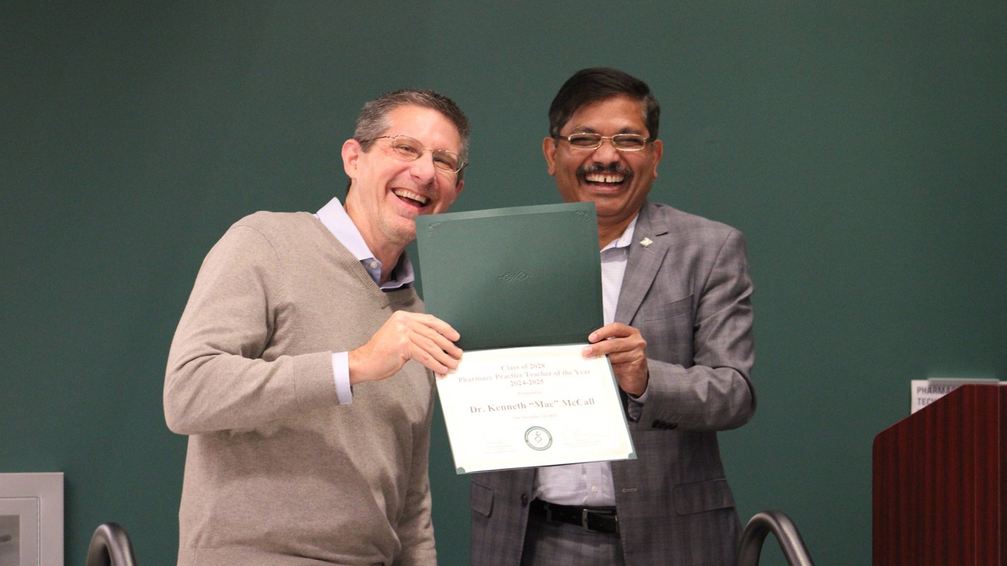 Chair and Clinical Professor of Pharmacy Practice Kenneth McCall accepting his Class of 2028 Best Teacher from the Pharmacy Practice Department award from Dean Nagaraju.