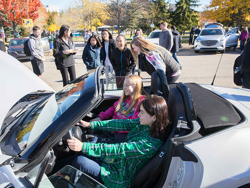 SOM students study a Mazda vehicle as part of a project to analyze and present solutions to Mazda Motor executives on how to engage a younger generation and make them want to buy its cars.