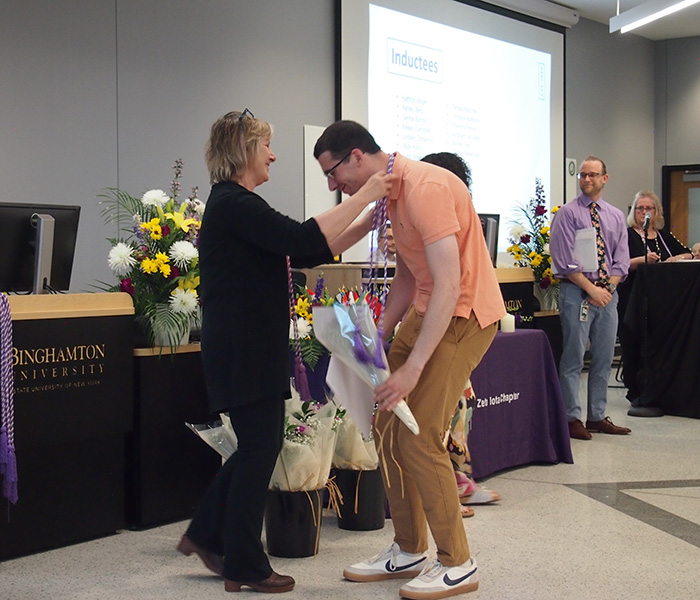 Associate Professor Judith Quaranta '79, MS '98, PhD '13, places a Sigma Theta Tau honor cord around the neck of senior nursing student Abraham Sangeap, one of 13 students inducted into the nursing society. Graduating students wear the cords over their robes at Commencement to signify their academic achievement in the field of nursing.