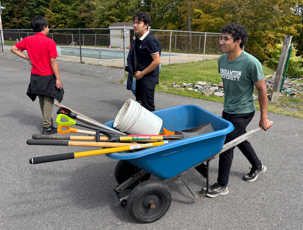 Sean Stevenson, sophomore neuroscience and biomedical engineering student, pushes a wheelbarrow full of tools to begin work on hiking trails at PAL Camp in Binghamton.