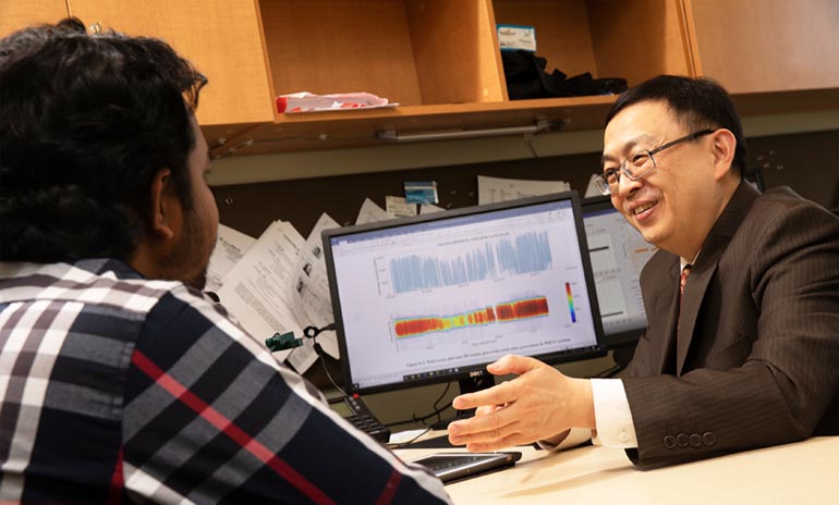Ning Zhou, an associate professor of electrical and computer engineering, meets with graduate student Tawsif Ahmad.