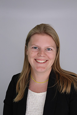 A woman wearing a black blazer and white shirt smiling