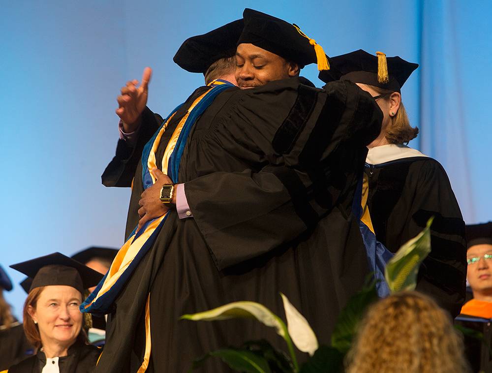 Jared McShall gives professor Matthew Johnson a hug after he was hooded with a PhD in clinical psychology during the Graduate School Commencement Ceremony held at the Events Center.