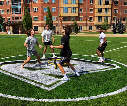 four teenage boys playing spikeball in the B