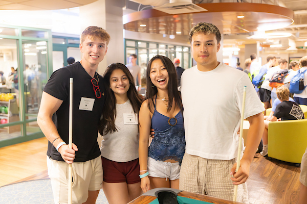 A group of students smiling while playing pool.