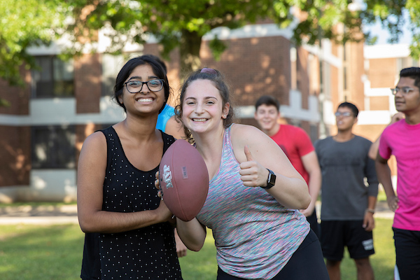 Students smiling while playing Co-Rec Football.