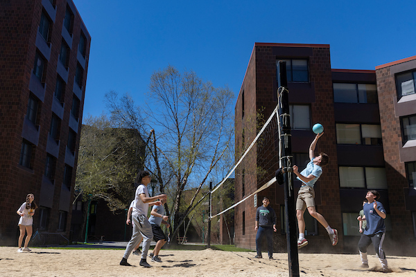 Students playing volleyball on a CIW sand court.
