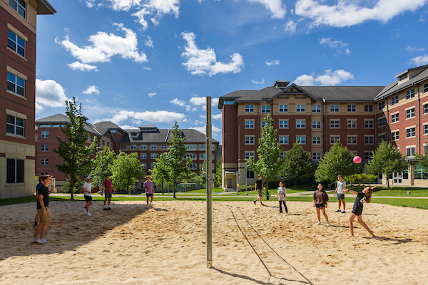 Students playing sand volleyball on a Newing court.