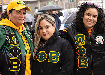 Three members of a Binghamton University Greek-letter organization posing together at a campus event.