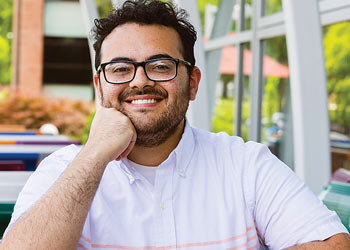 Binghamton University student smiling while seated outdoors on campus.
