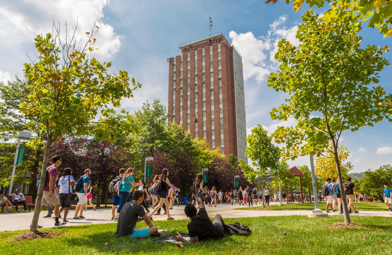 an upwards shot of students walking below the library tower on a summer day