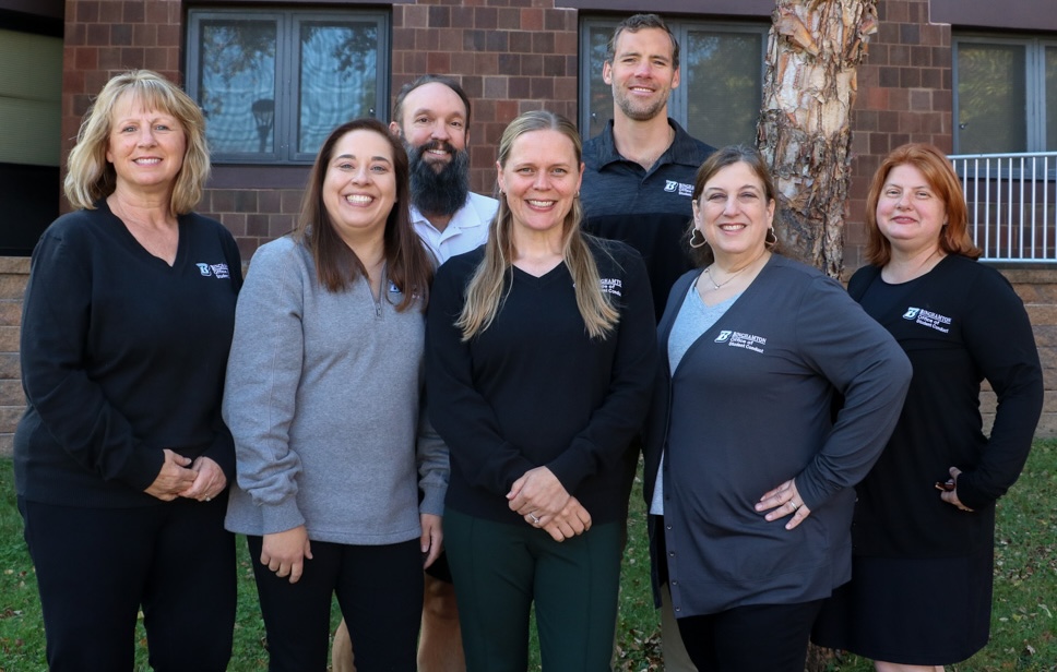 the conduct team in binghamton apparel gathered in front of a brick wall